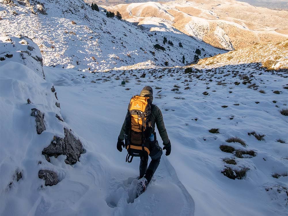 Hiker walking in deep snow in mountains