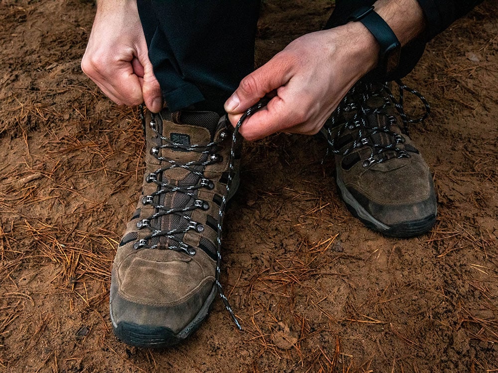 A hiker tieing laces of hiking boots outdoors