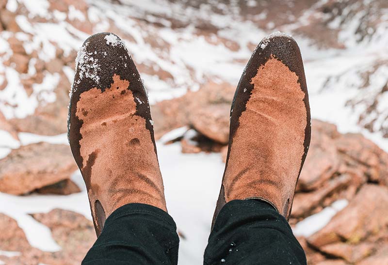 A man wearing cowboy boots whil hiking in the mountains in snow