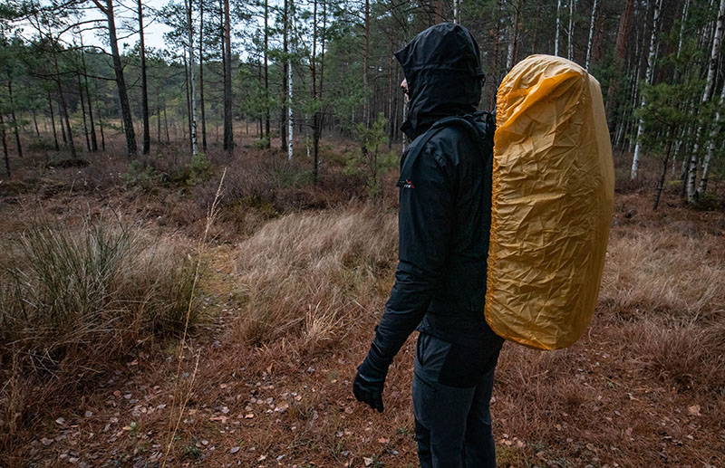 A hiker wearing rain gear for hiking in rain: a rain jacket and a rain cover for backpack
