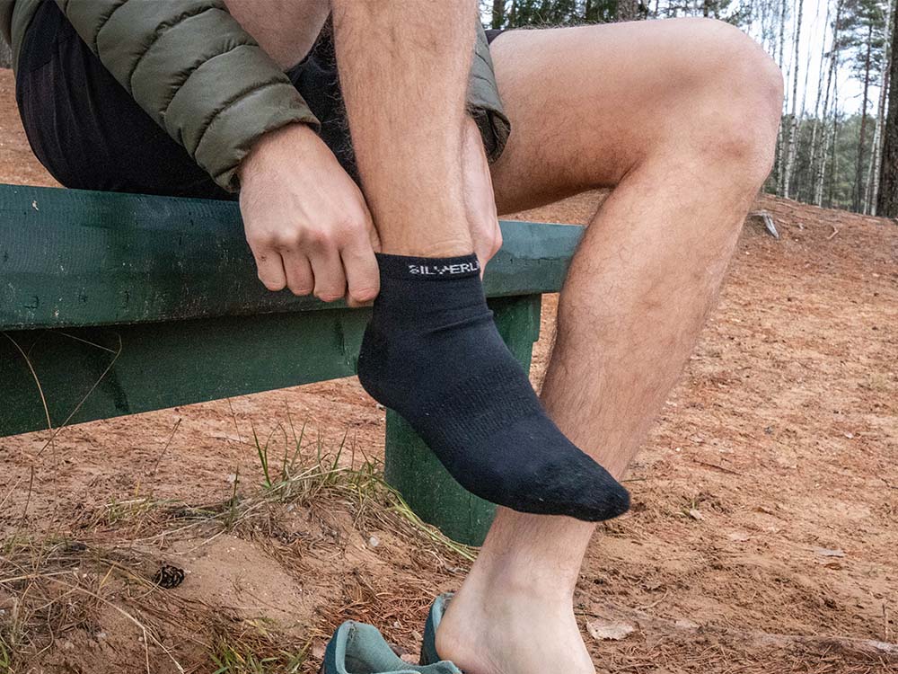 A person putting on a pair of merino wool ankle hiking socks